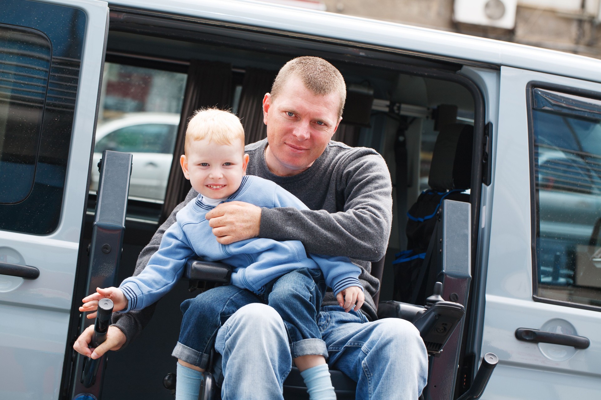 A man in a wheelchair holding a young child